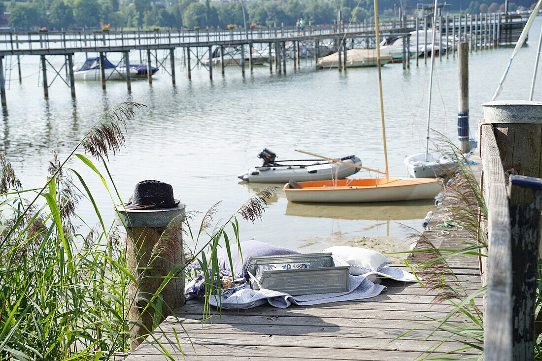 Wooden jetty on the lake with boats, reeds in the foreground