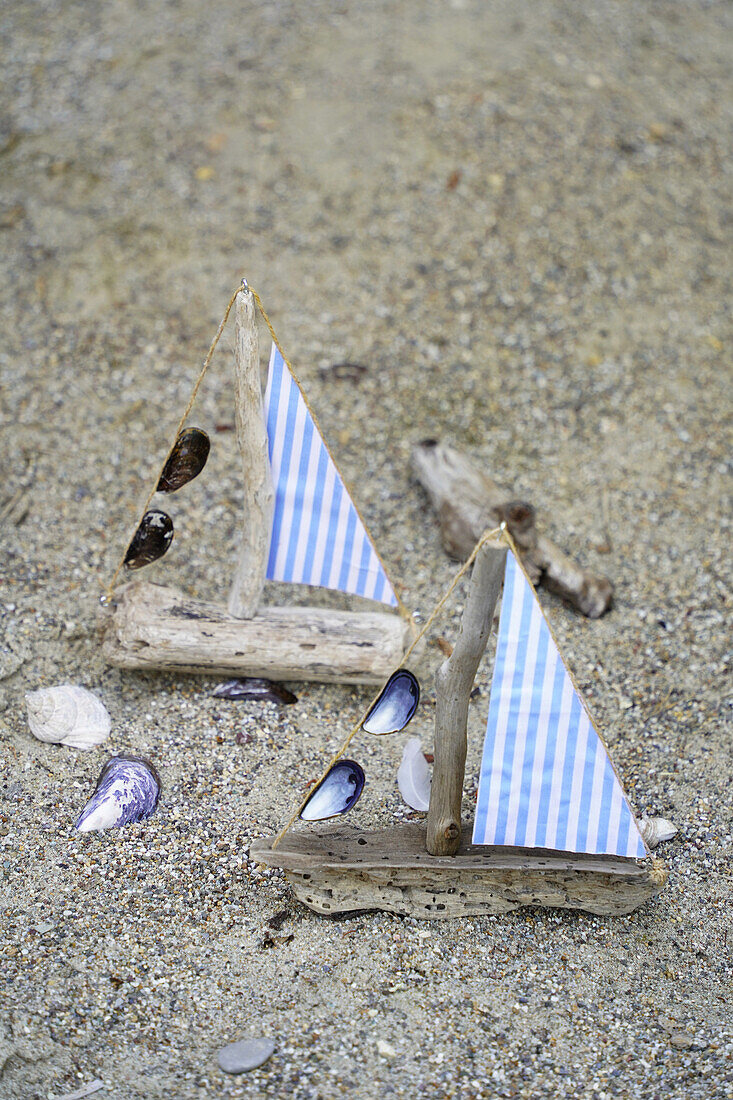 DIY sailboats made from driftwood and fabric scraps on a sandy beach