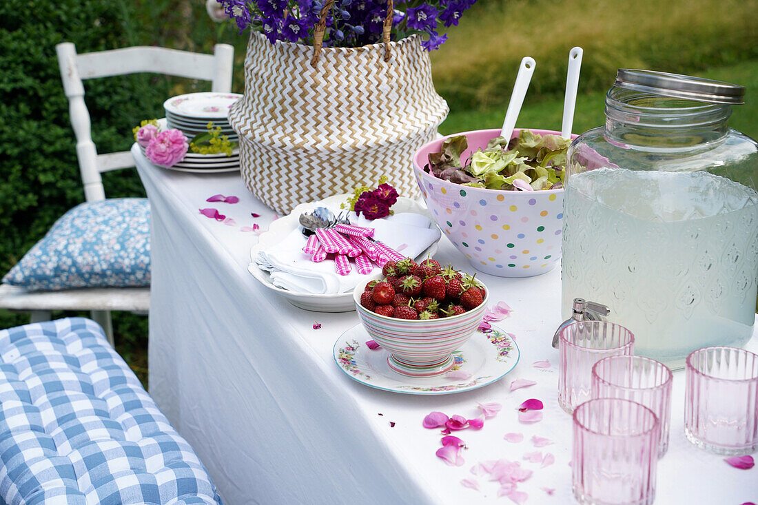 Gedeckter Sommertisch mit Erdbeeren und Salat und mit Rittersporn