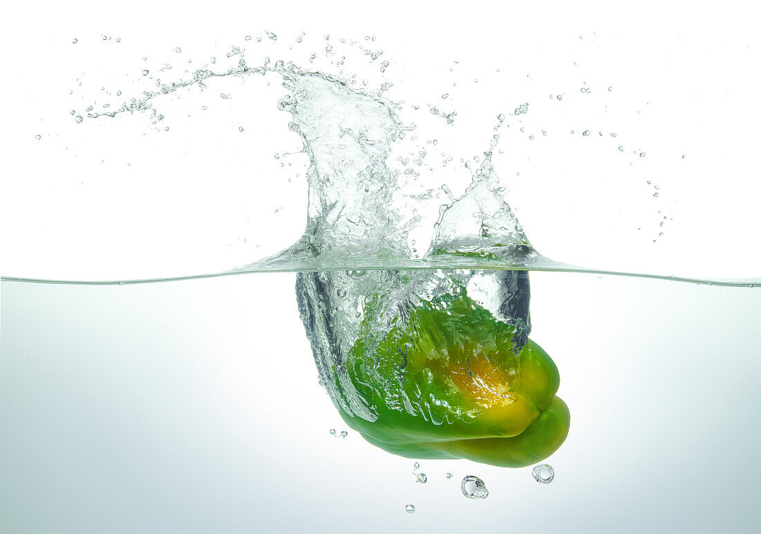 Green pepper splashing in water