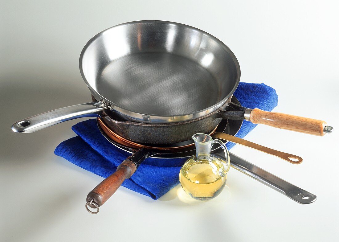 Various pans in a pile and bottle of oil