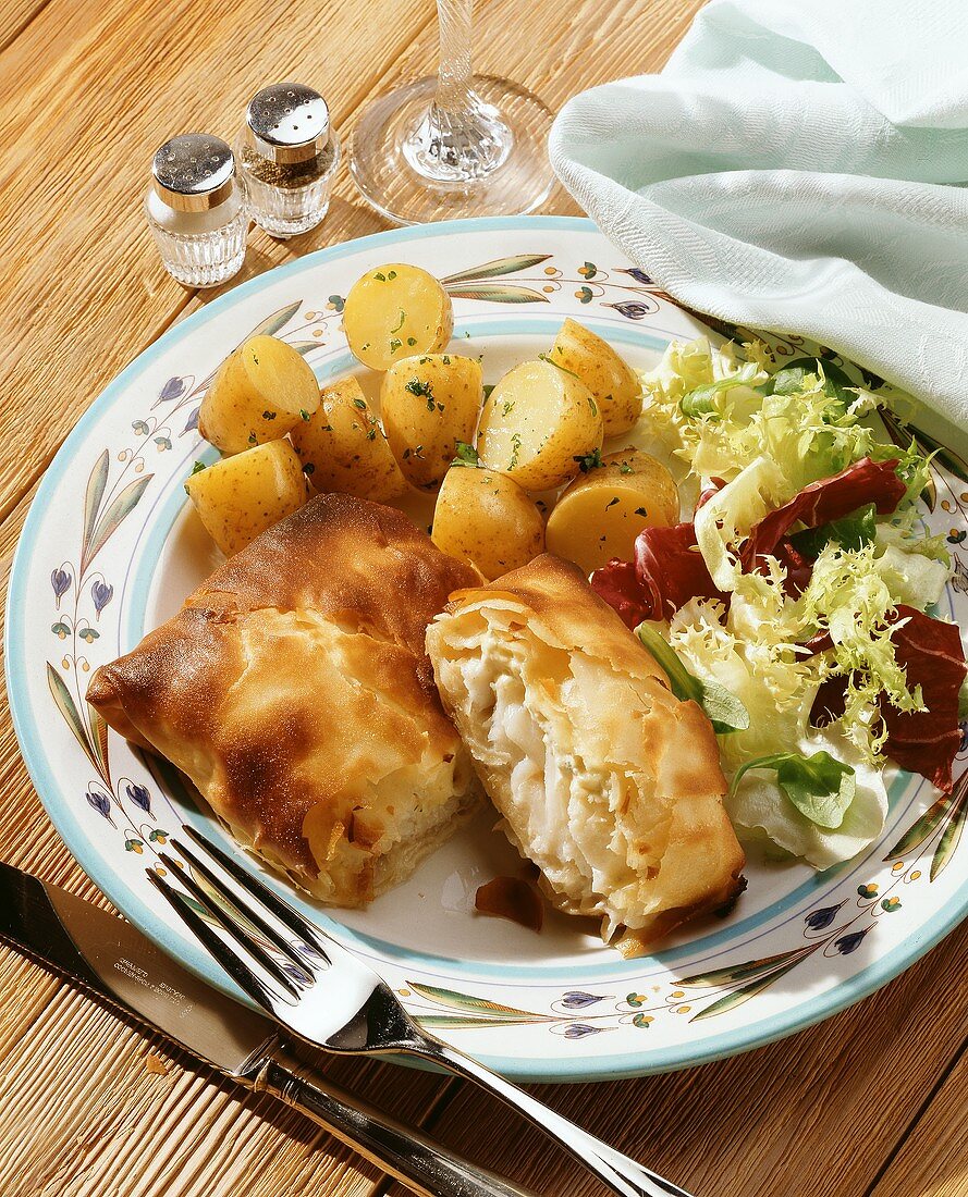 Haddock in filo pastry with potatoes & salad on plate