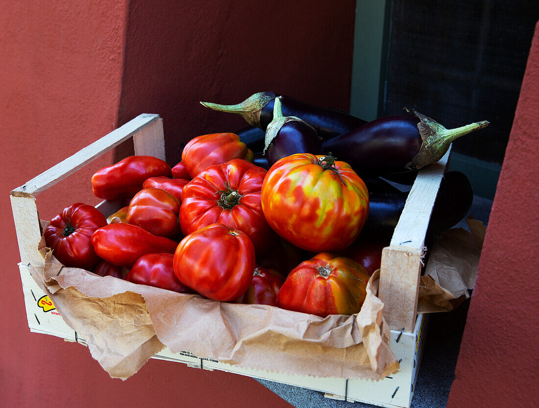 Fresh tomatoes and aubergines in a wooden crate