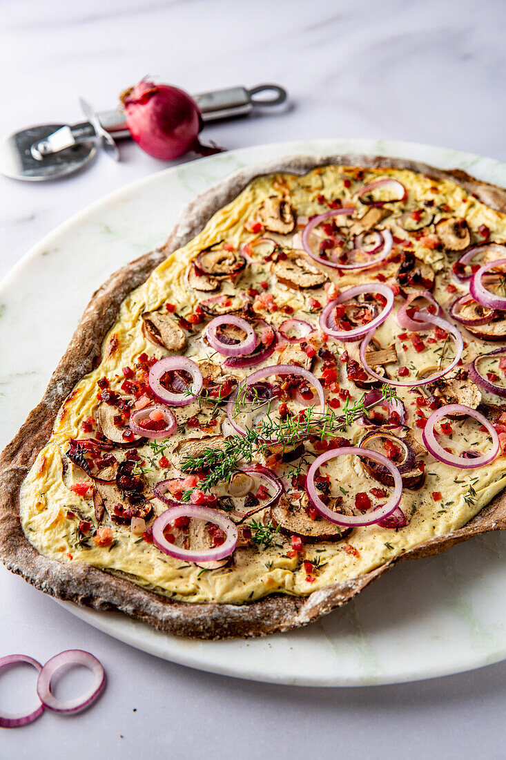 Linseed flour tarte flambée with red onions, mushrooms and bacon