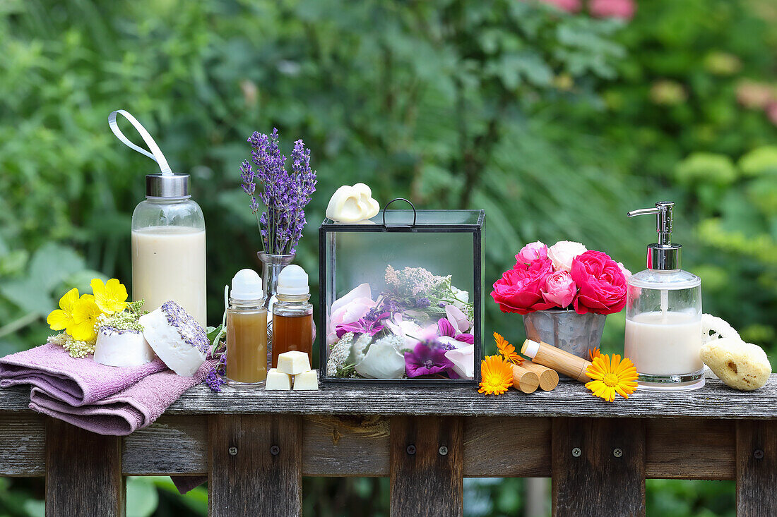 Naturkosmetik und Blumenarrangement auf rustikalem Holztisch im Garten