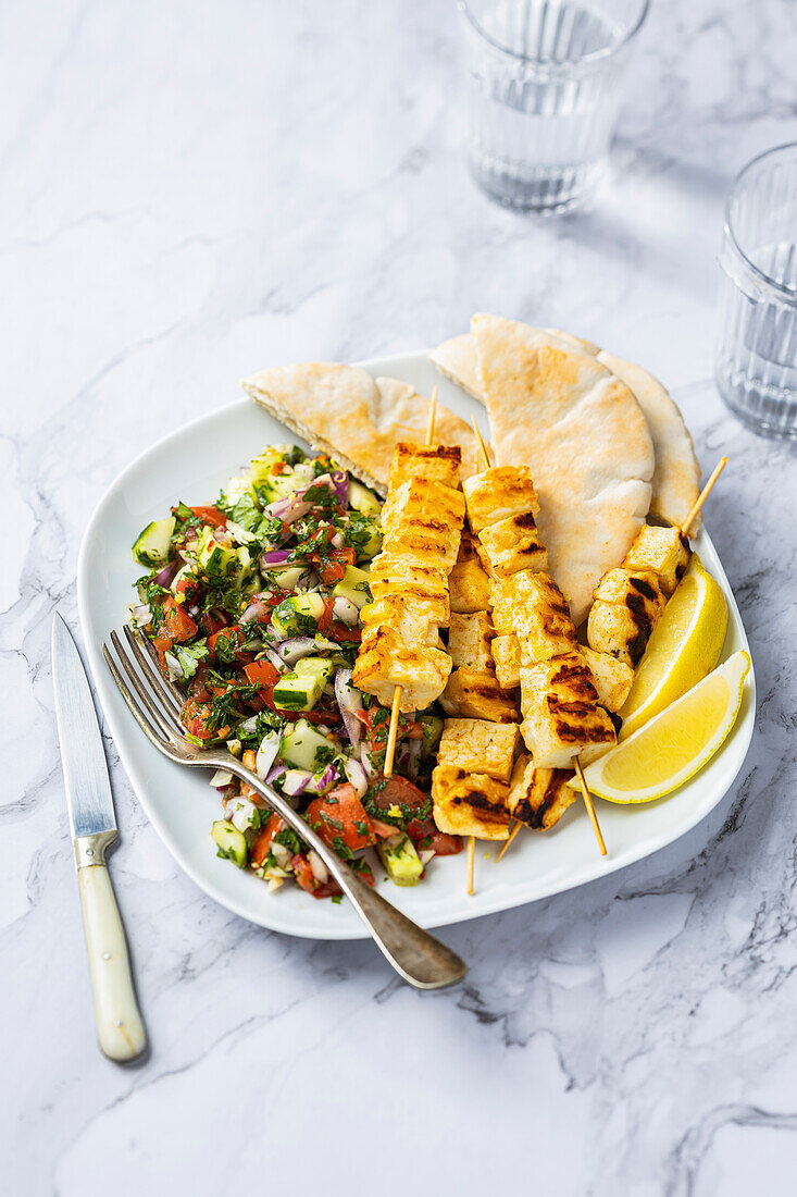 Grilled halloumi skewers with tomato and cucumber salad and pita bread