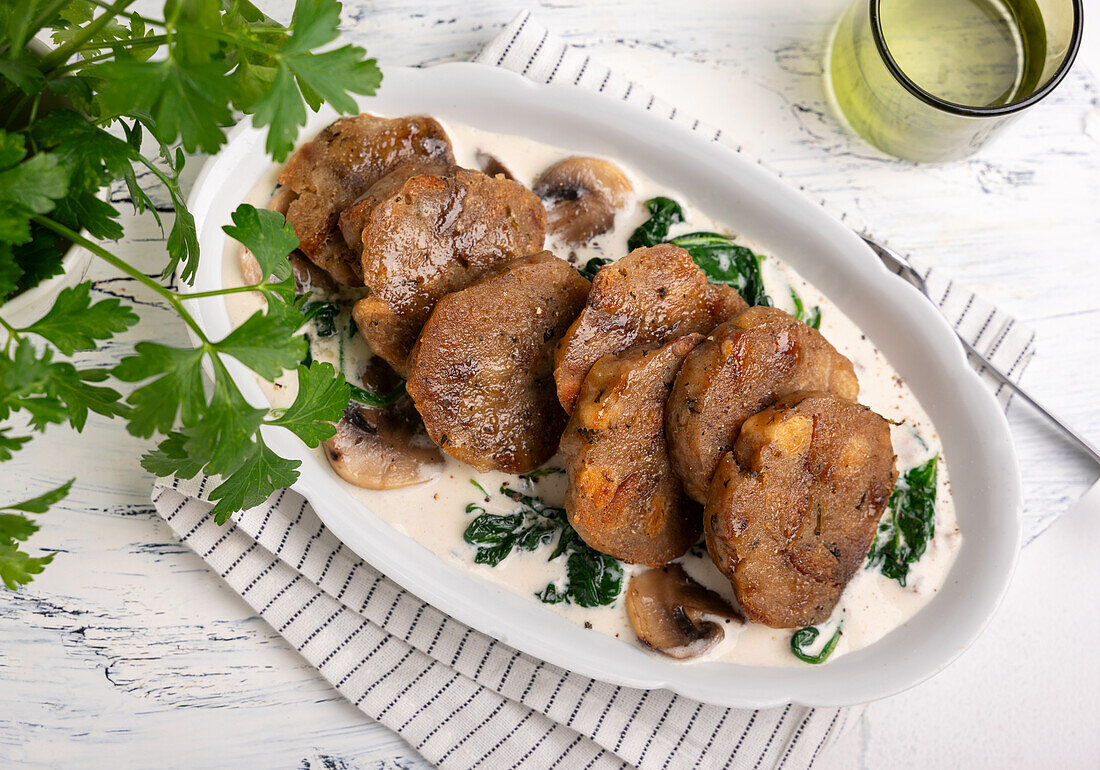 Fried bread dumpling slices on mushroom and spinach cream