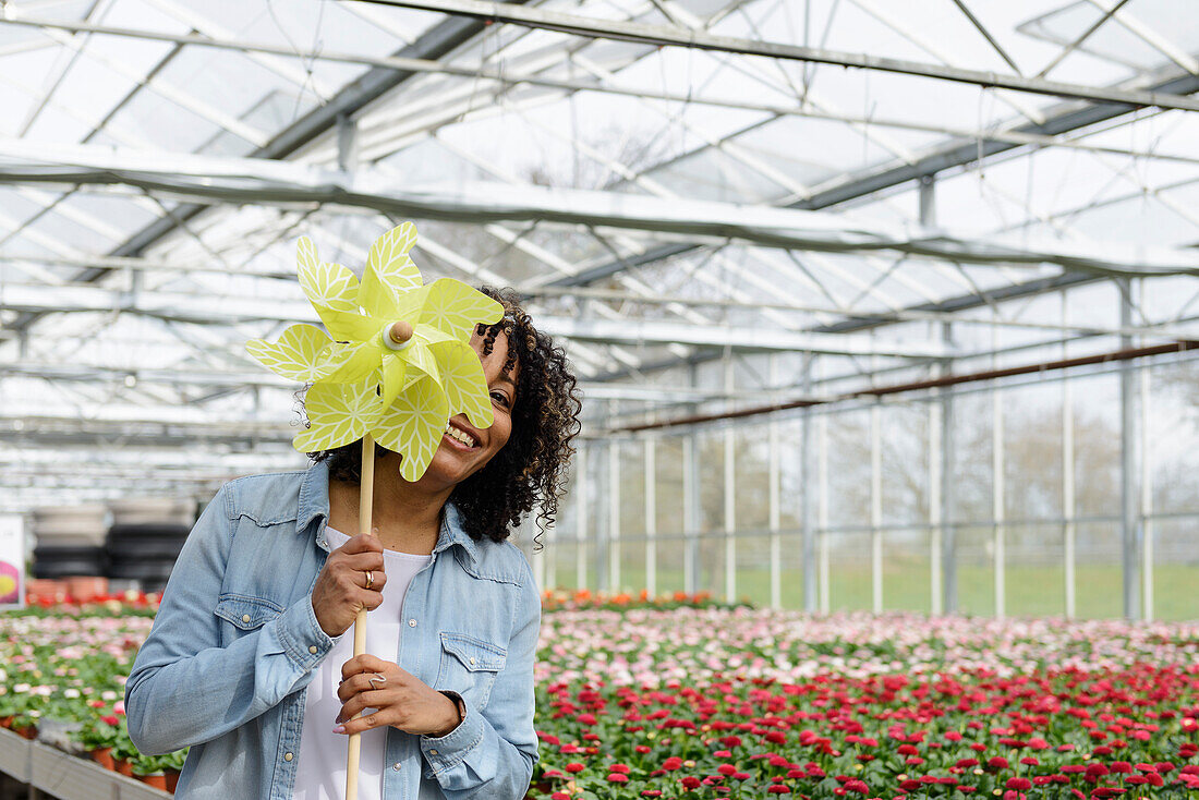 Smiling young woman in nursery with plastic windmill