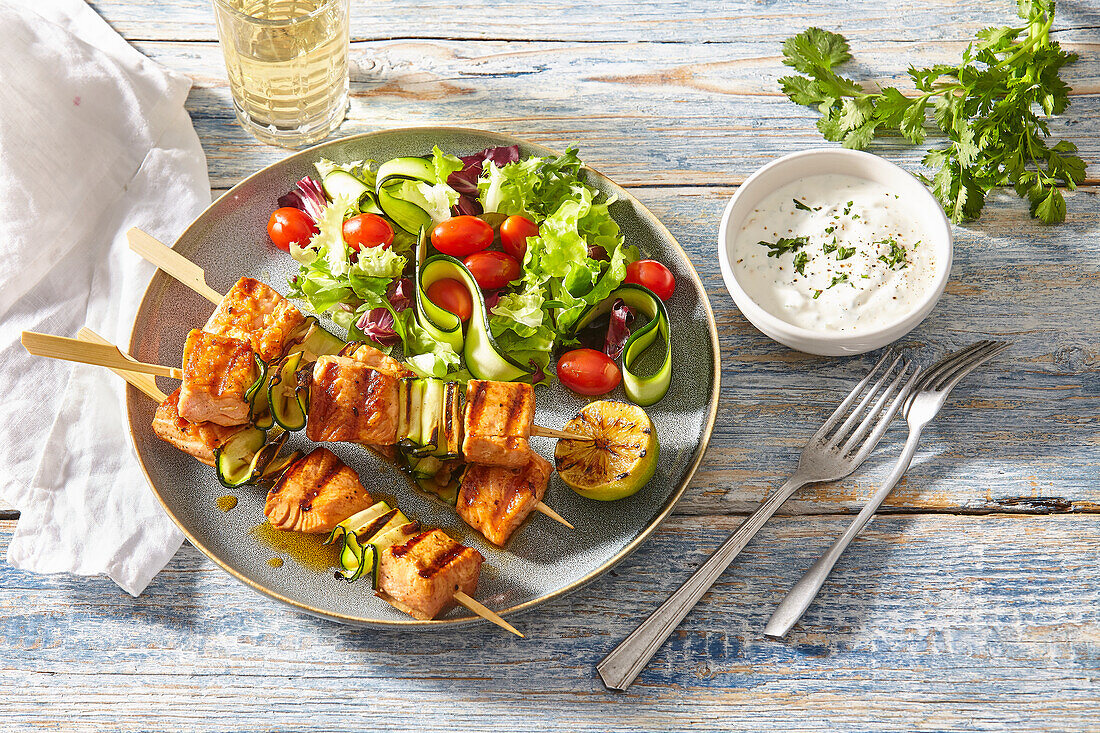 Grilled salmon skewers with mixed salad and yoghurt dip