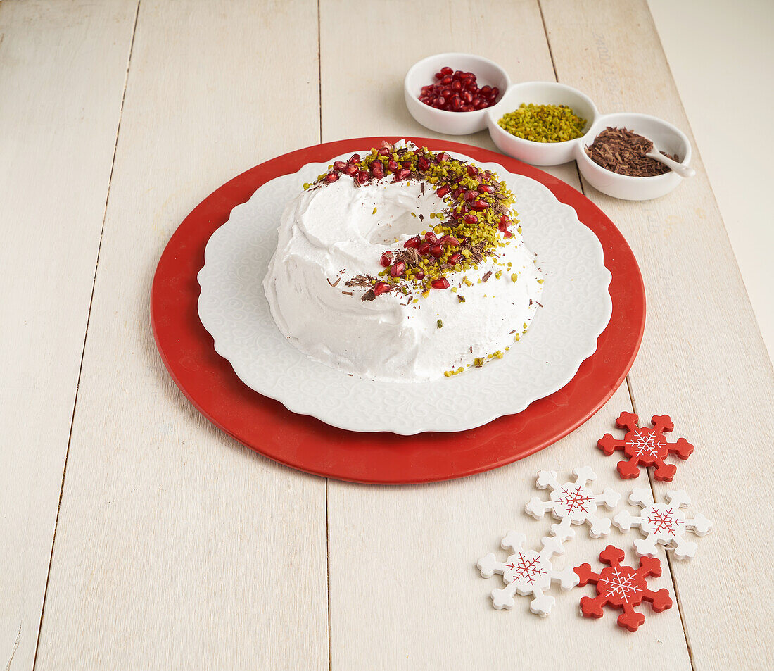 Donut cake with white icing, pistachios, pomegranate seeds and chocolate