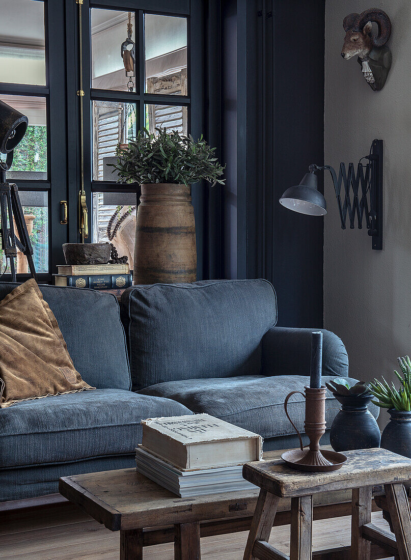 Blue velvet sofa with wooden furniture, vintage decor and plants in the living room