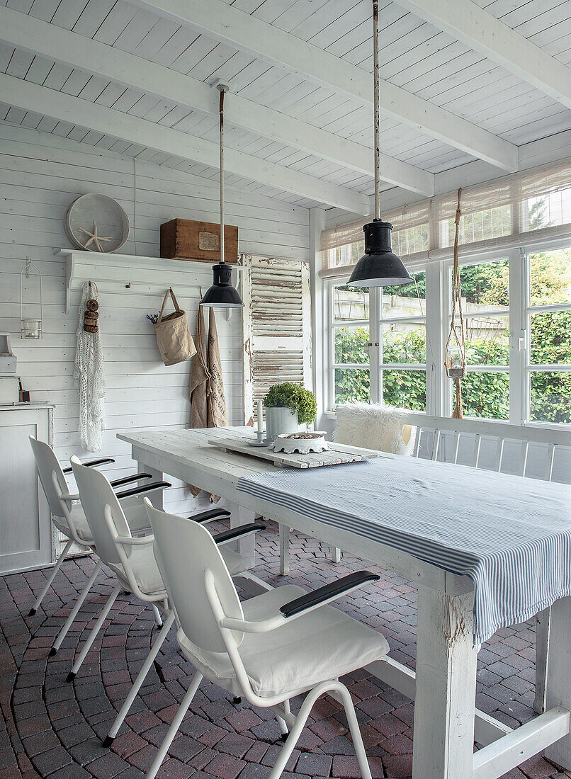 Country-style dining area with white wooden furniture and large windows