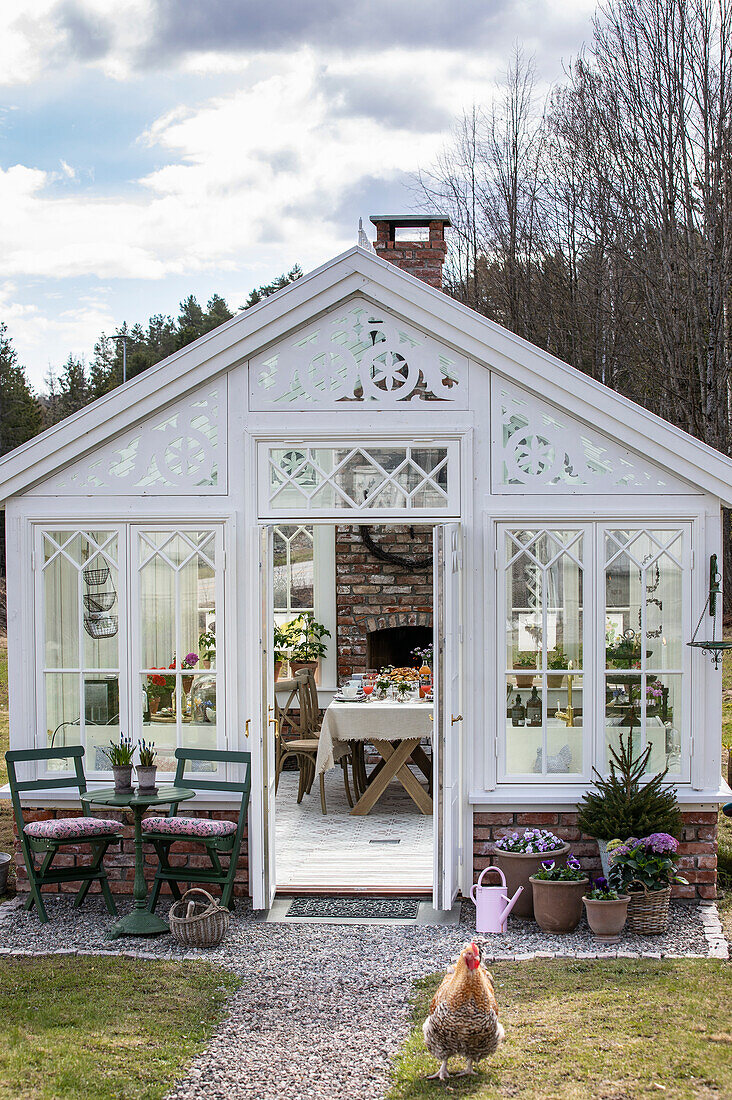 White greenhouse with group of tables, plants and decorative elements in the garden