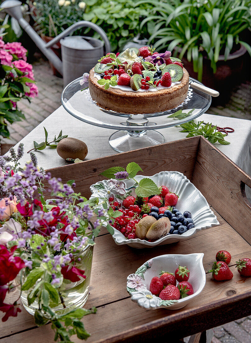 Sommertorte mit frischen Beeren und Kiwi auf einer Gartenterrasse