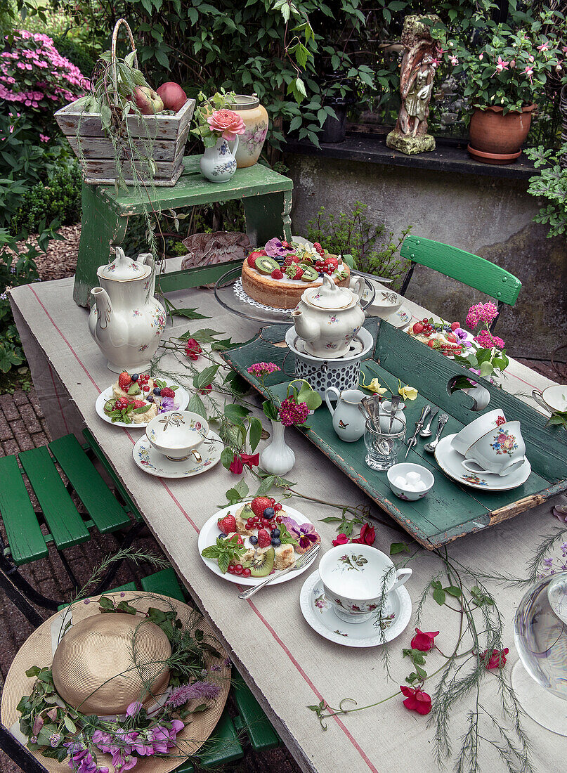 Gedeckter Gartentisch mit Vintage-Porzellan, umgeben von Blumendeko