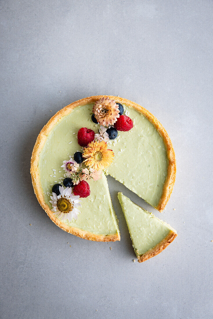 Vegan avocado and coconut tart with flower decoration and berries