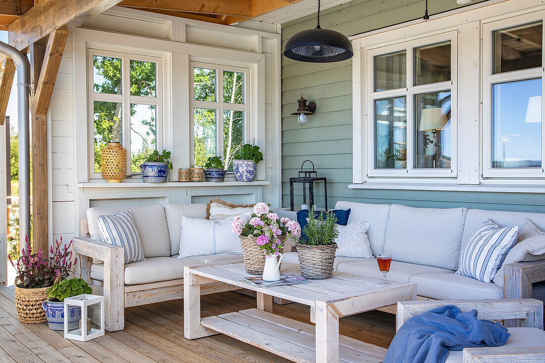 Gepolsterte Holzsofa-Ecke mit Pflanzen und Laterne auf der Veranda