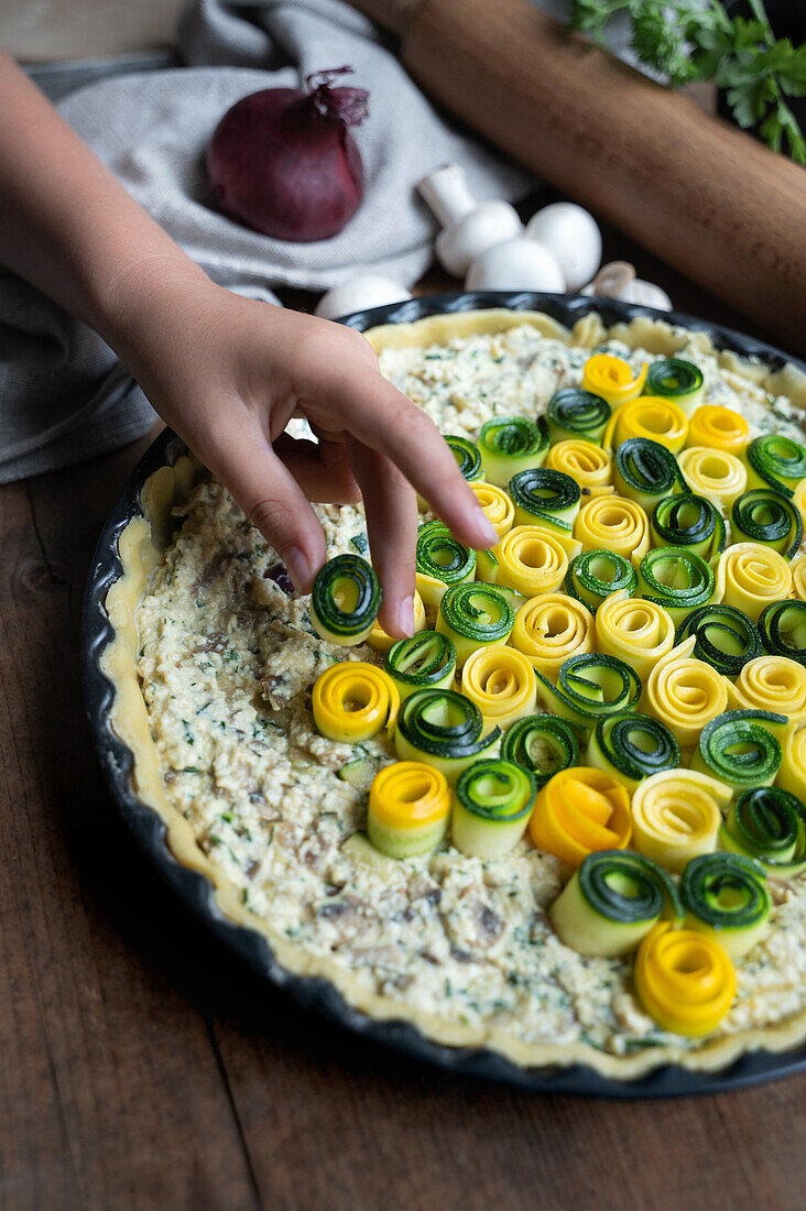 Child topping vegan quiche with courgette rolls