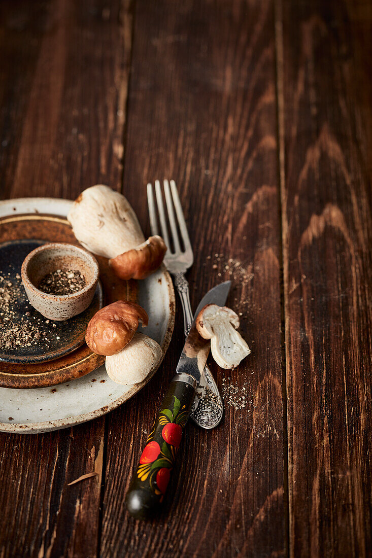 Autumnal, rustic table setting with fresh porcini mushrooms and coarsely crushed pepper