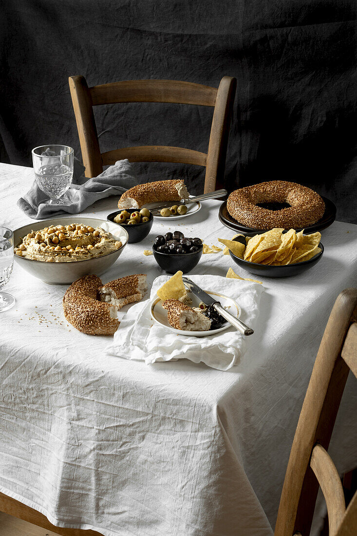 Table setting with hummus, olives, corn chips and sesame bread