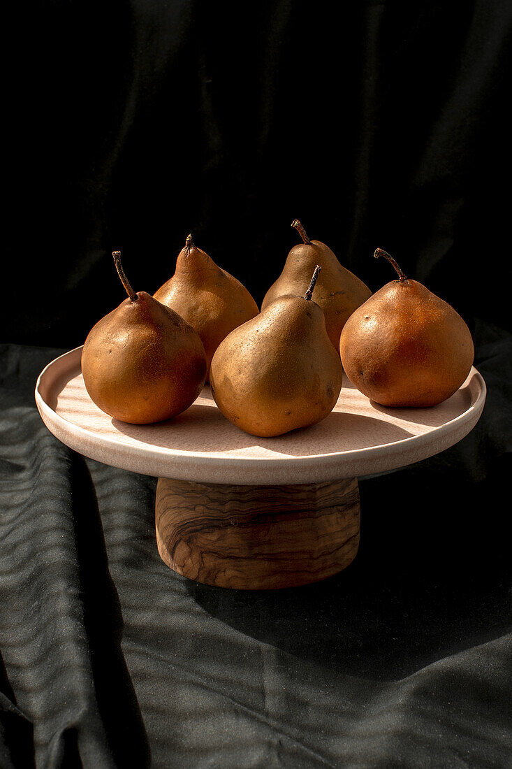 Pears on plate in front of black background