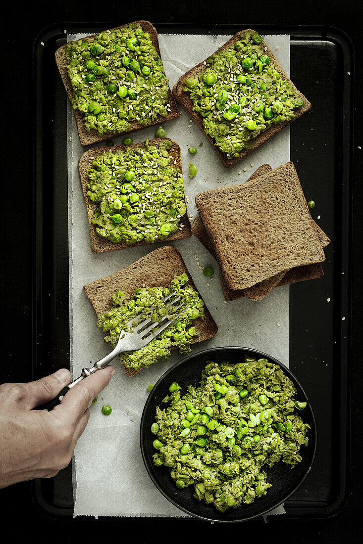 Erbsencreme wird auf Toastscheiben gestrichen