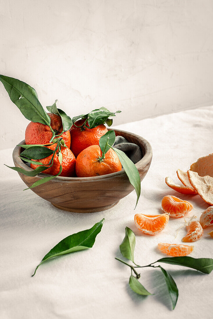 Mandarinen mit Blättern in Holzschüssel