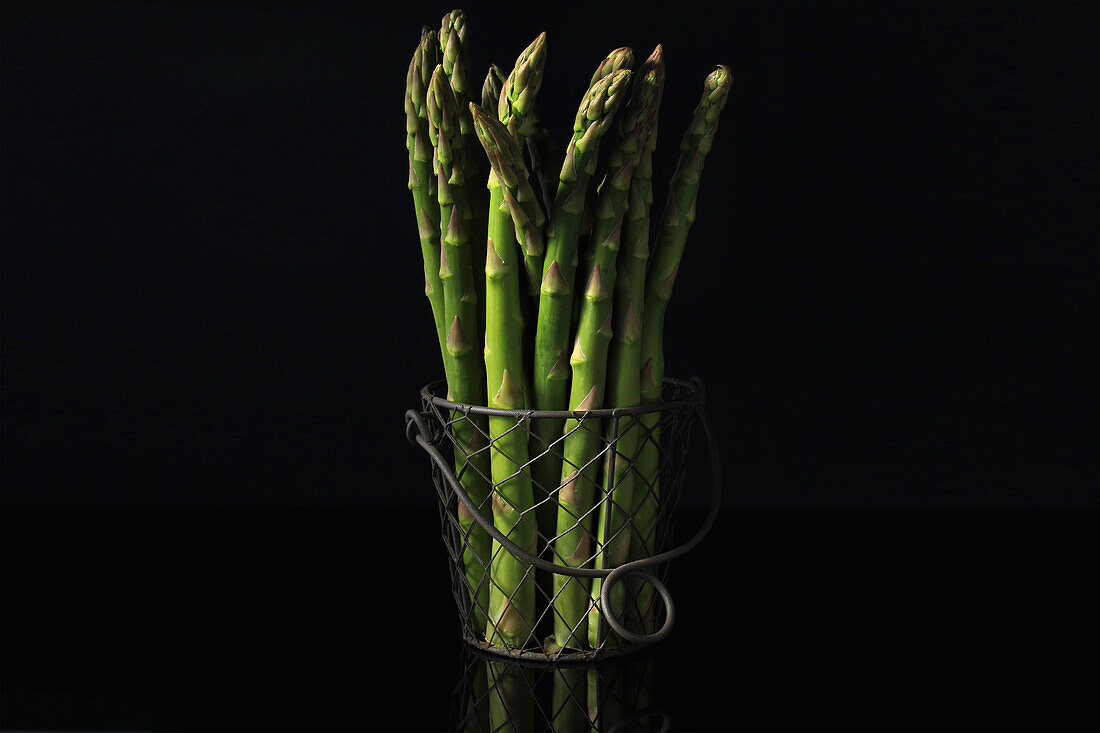 A bunch of green asparagus in a wire basket