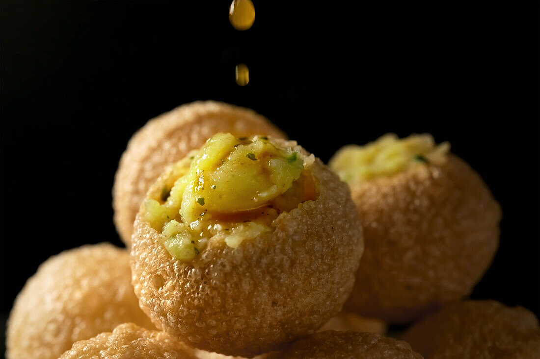 Panipuri - deep-fried Indian dough balls filled with spiced mashed potato and drizzled with tamarind water