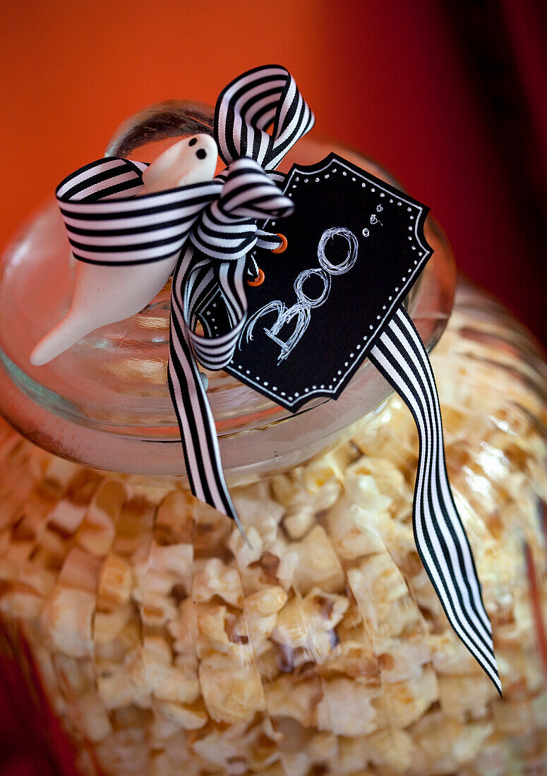 Popcorn im Glasbehälter mit Halloween-Deko und "Boo"-Anhänger