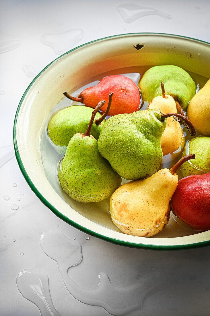 Selection of red, green and yellow pears in water