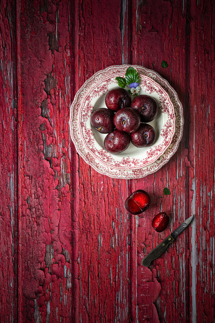Plums on a red wooden background