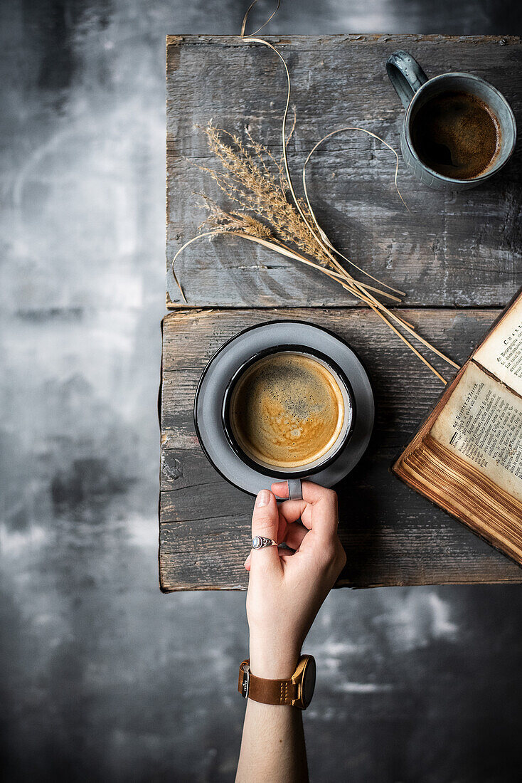 Kaffeetasse mit Hand und Buch