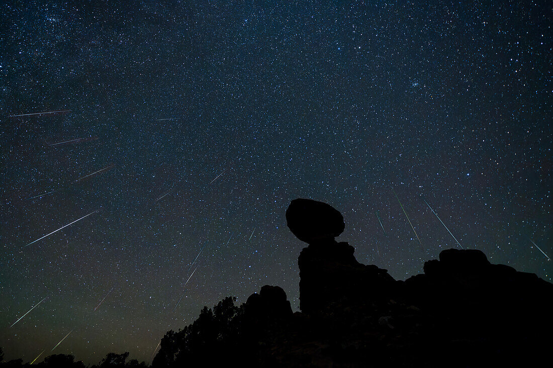 Geminiden-Meteoritenschauer über dem Balanced Rock im Arches National Park in Utah. Das zusammengesetzte Bild zeigt 23 Meteoriten über einen Zeitraum von 2 Stunden