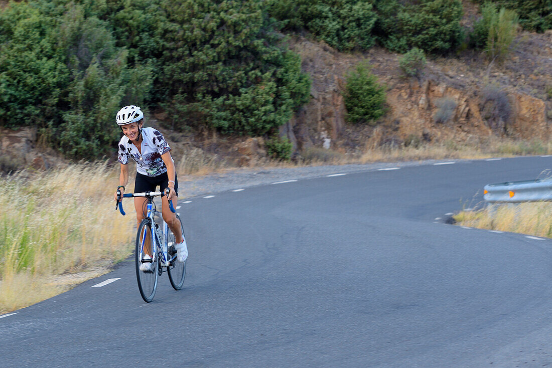 A woman climbing on bicycle the mountain pass of Arrebatacapas in Cebreros, province of Ávila.