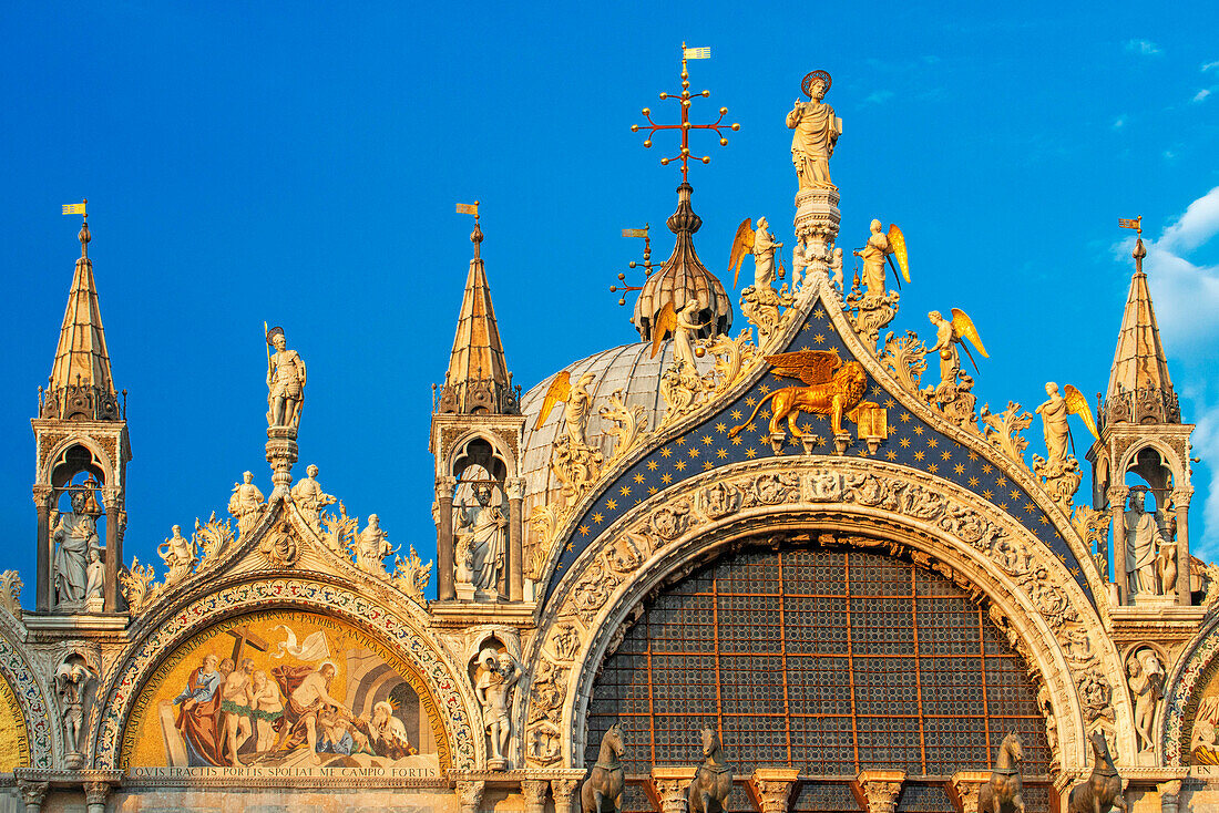 Die Basilika San Marco spiegelt sich im Wasser auf dem Markusplatz in der Dämmerung während des Sonnenuntergangs, Venedig, Italien, mit Bewegungsunschärfe auf den Touristenmassen