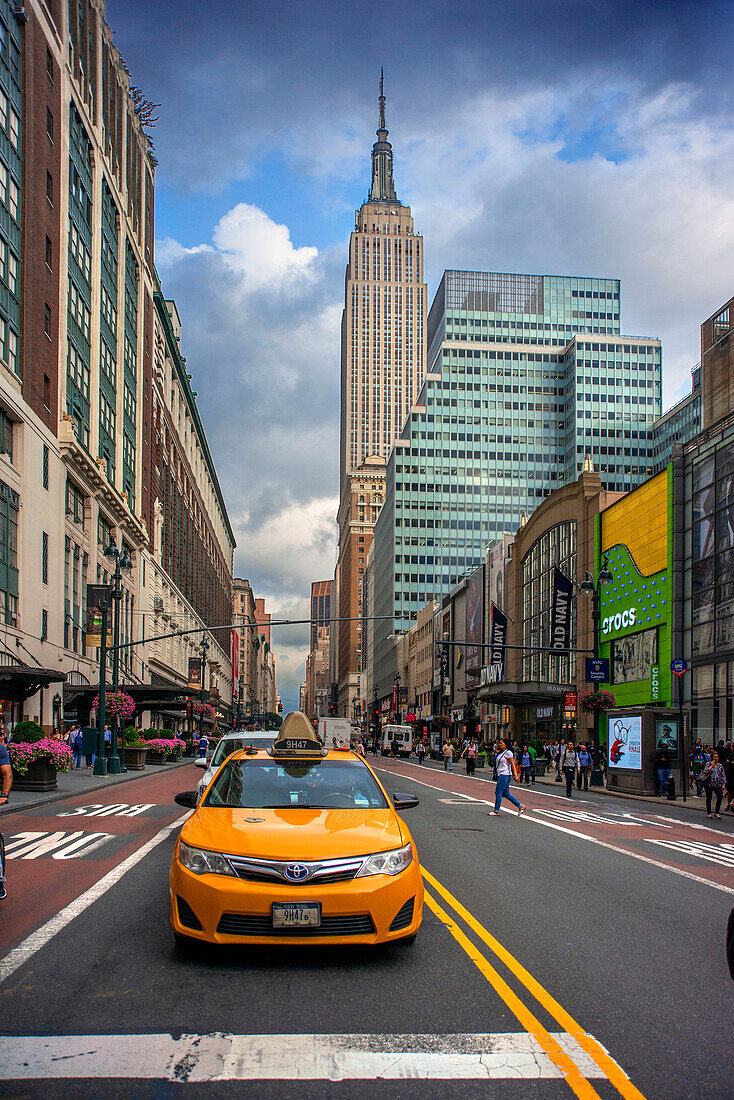 Traditionelles gelbes NYC-Taxi, Empire State Building im Hintergrund, USA