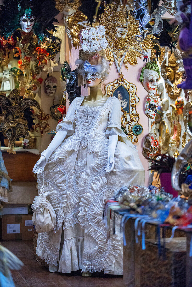 Verschnörkelte Karnevalsmaske zwischen bunten Federn in Venedig, Italien. Eine Ausstellung von Masken für Maskenbälle und venezianischen Masken in Bardolino am Gardasee, Region Venetien, Italien