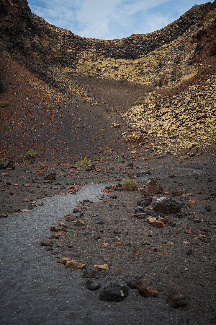 Volcan del Cuervo (Krähenvulkan), ein Krater, der über einen Rundweg in einer kargen, felsigen Landschaft erkundet wird