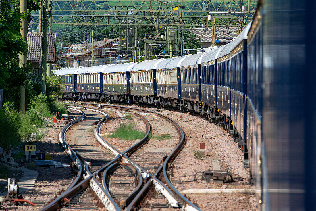 Train running along Renon plateau with Dolomites scenery. Belmond Venice Simplon Orient Express luxury train.