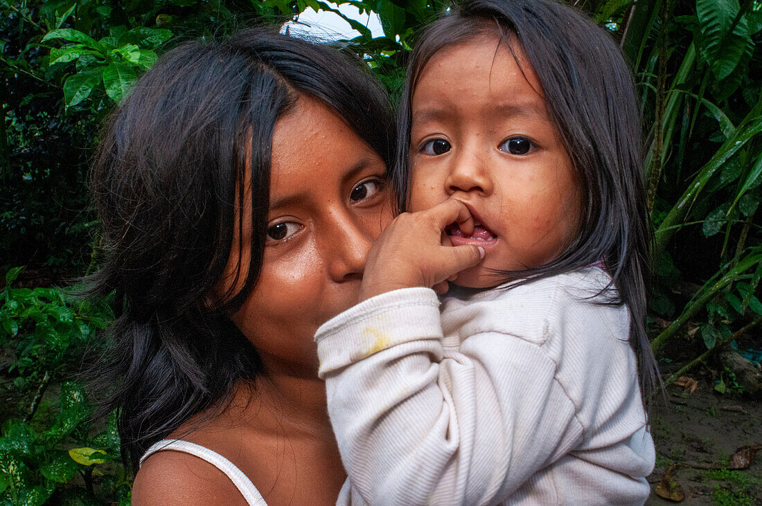 Ein Mädchen kümmert sich um ihre Schwester, während ihre Eltern arbeiten, einheimische Familie im Flussdorf Timicuro I. Iqutios am peruanischen Amazonas, Loreto, Peru