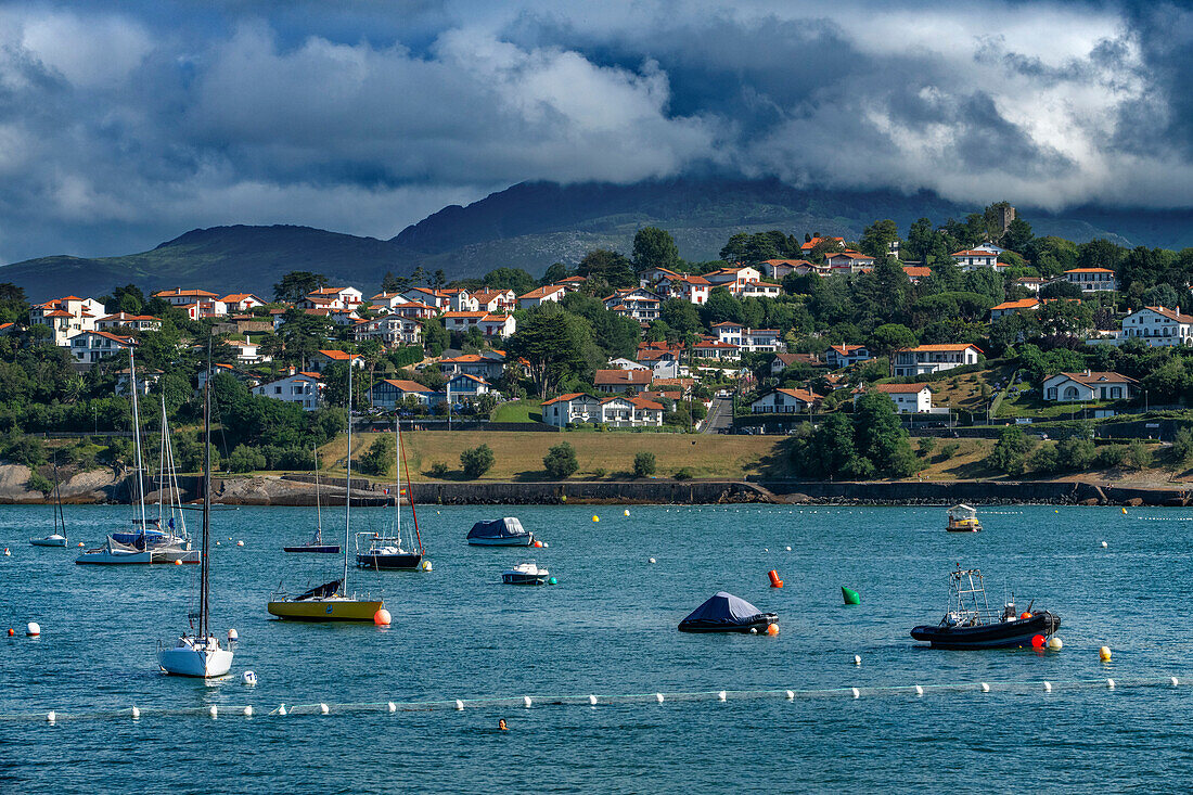 The Rhune mountain overlooking Ciboure Basque country. France Small coloreful fish boats on the old port of cituadel in front of Saint Jean de luz.