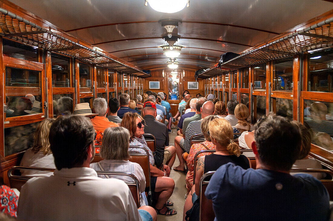 Touristen im Inneren des Tren de Soller, eines historischen Zuges, der Palma de Mallorca mit Soller verbindet, Mallorca, Balearen, Spanien, Mittelmeer, Europa