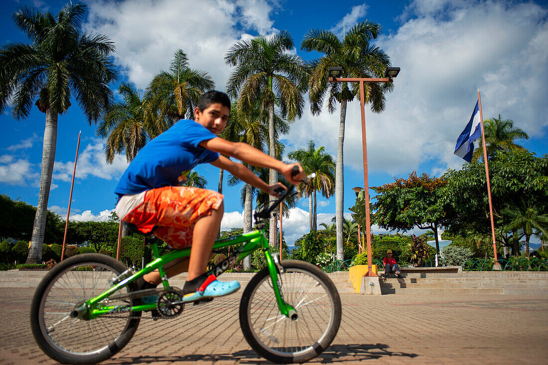 Junge auf einem Fahrrad im Zentralpark von Nahuizalco Sonsonate El Salvador Zentralamerika. Ruta De Las Flores, Departement Sonsonate