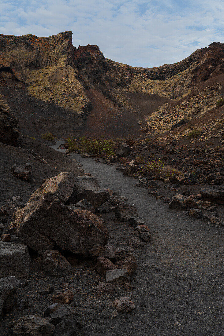 Volcan del Cuervo (Krähenvulkan), ein Krater, der über einen Rundweg in einer kargen, felsigen Landschaft erkundet wird