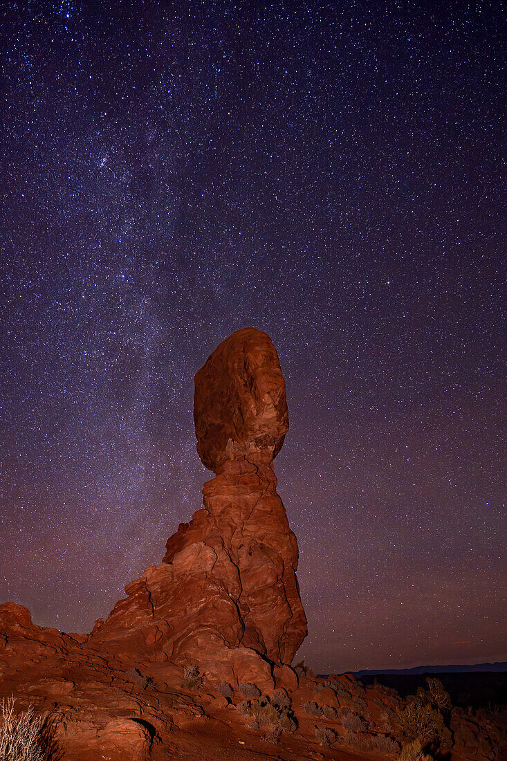 Northern end of the Milky Way over Balanced Rock in Arches National Park in winter in Utah.