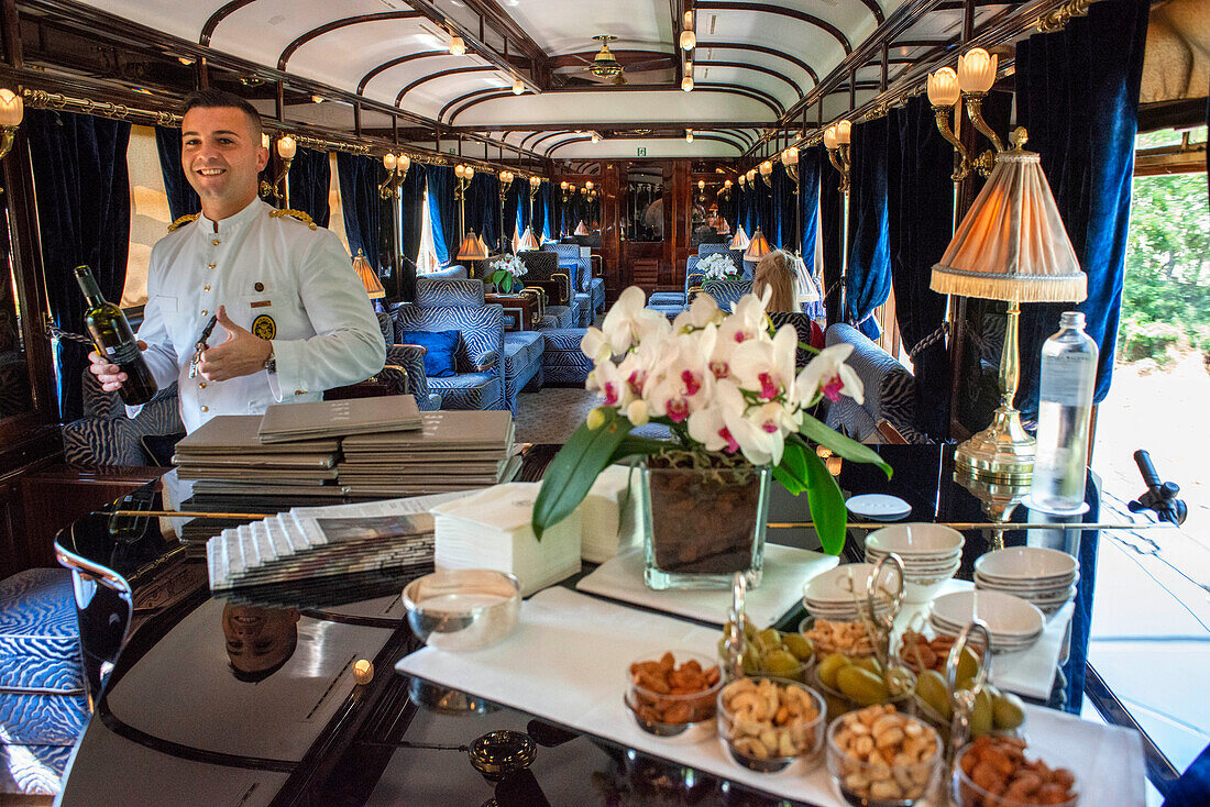Ein Kellner serviert Wein im Art-Deco-Barwagen des Luxuszuges Belmond Venice Simplon Orient Express