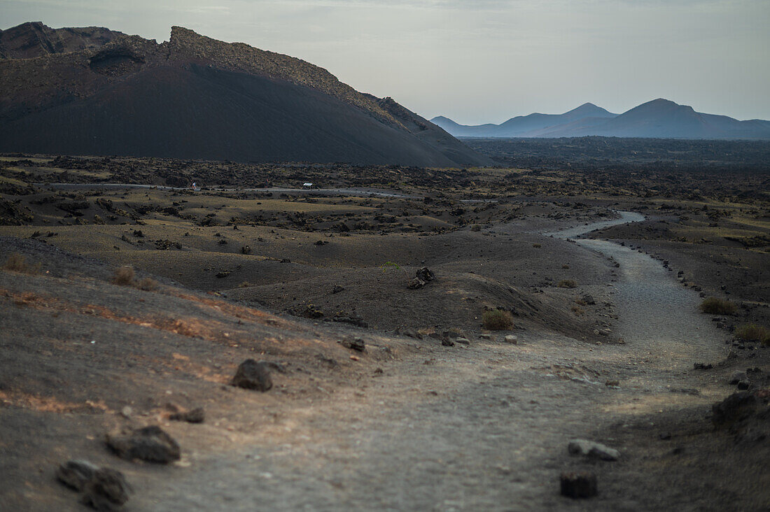 Volcan del Cuervo (Krähenvulkan), ein Krater, der über einen Rundweg in einer kargen, felsigen Landschaft erkundet wird