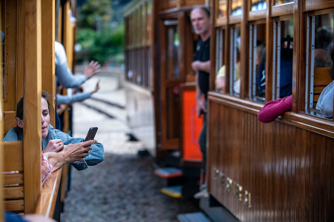 Touristen in der historischen Straßenbahn am Hafen von Soller. Die Straßenbahn verkehrt auf einer Strecke von 5 km zwischen dem Bahnhof im Dorf Soller und dem Puerto de Soller, Soller Mallorca, Balearen, Spanien, Mittelmeer, Europa