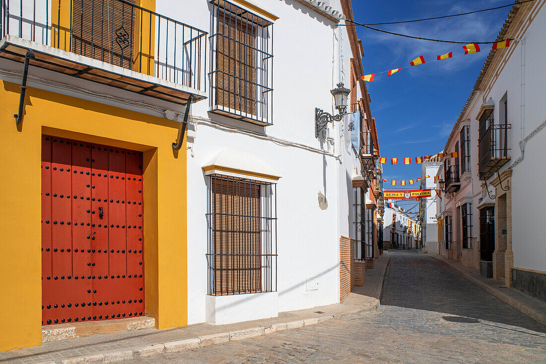 Spanische Flaggen und weiße Häuser in der Altstadt von Marchena in der Provinz Sevilla in Andalusien im Süden Spaniens